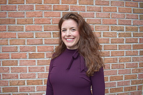 Director, Communications and Marketing, Jecoliah Daniels, smiles in front of Infinite Legacy's office.