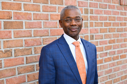 Director, Information Technology, Ondray Muhammad, smiles in front of Infinite Legacy's office.