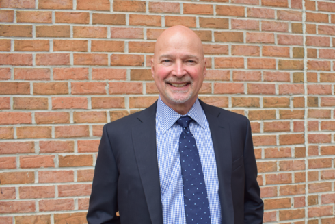 Vice President and Chief Financial Officer, Scott Hartranft stands outside of Infinite Legacy’s office smiling.